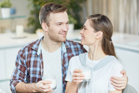 Yougn 的男人和女人看着彼此的牛奶和早餐交谈