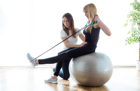 理疗师帮助病人在理疗室健身球运动