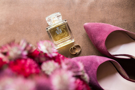 金色婚礼戒指, 香水, 新娘鞋在棕色背景。婚庆配件