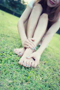 轻松的亚洲年轻女子光着脚坐在草地上