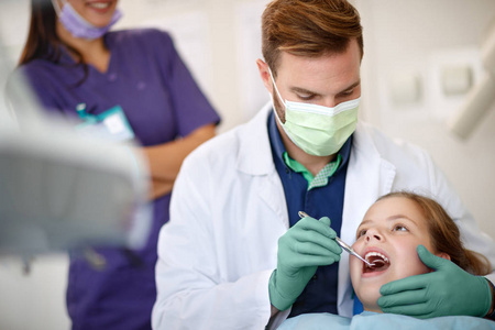 牙科镜检查儿童牙齿的男性牙医