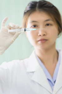 亚洲年轻医生女人与注射器在医院