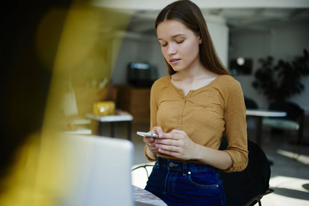 阿那亚图书馆沉思的时髦女孩聊天与最好的朋友在社交网络上手机短信