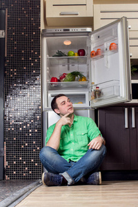 年轻人坐在冰箱前图片