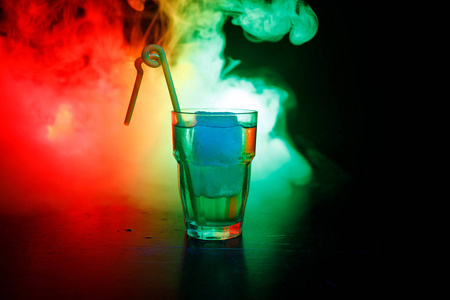 酒精鸡尾酒在玻璃与冰在烟雾在黑暗的背景。俱乐部饮料的概念。一杯鸡尾酒。选择性聚焦