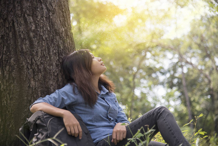 幸福的女人享受和放松的性质。年轻漂亮的女人，坐在绿色森林里的那棵大树下