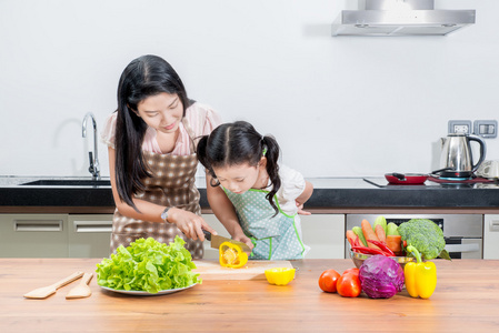 亚洲妈妈和孩子女儿在家里的厨房里做饭