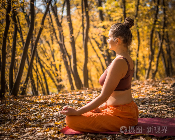 年轻女子在早晨秋天公园做瑜伽