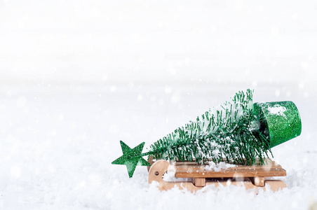 木制的冬天雪橇携带一小棵圣诞树