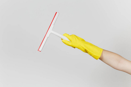 女性手的特写在黄色手套水平举行白色刮板为表面清洁与红色元素隔绝在白色背景。清洁用品的概念。复制广告空间
