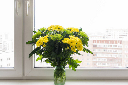 束黄色的菊花和绿色站在窗台上