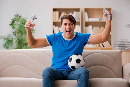 男人看足球在家里坐在沙发上