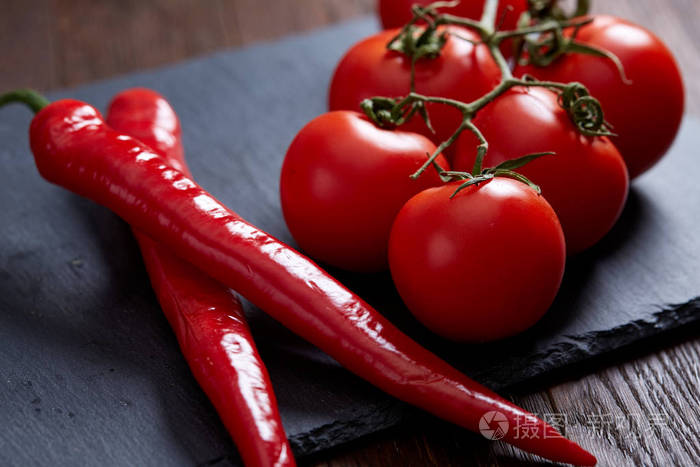 番茄束和辣椒在黑色板上的组成, 顶部视图, 特写, 选择性聚焦