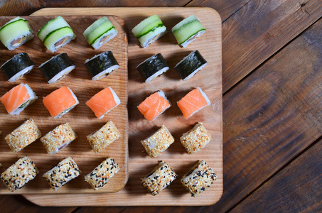 寿司套上的一些卷是位于一个木制的切割板上的一个餐桌上的厨房的寿司吧。传统的东方菜菜