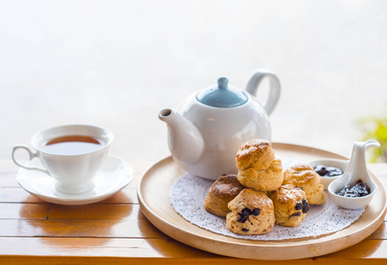 茶歇英式早餐和茶歇, 木桌上的烤饼和一杯带有模糊背景的茶照片