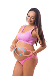 怀孕 生育。谁出生 女孩，男孩还是双胞胎。怀孕的母亲在肚子里抱着粉红色和蓝色的心
