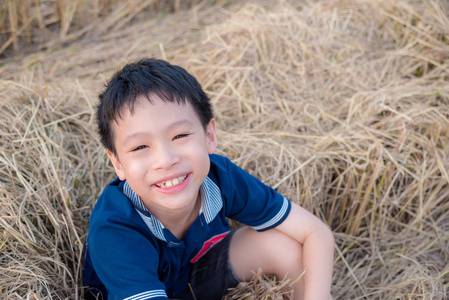 小男孩坐在干草中稻田后栽培