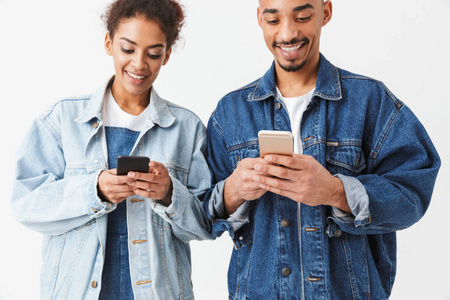 微笑的非洲夫妇在牛仔衬衫上写信息的智能手机