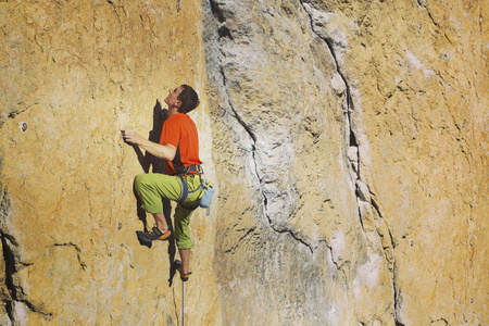 宽阔的山谷的背景与石灰石墙上爬的岩石 Climber.Young 人