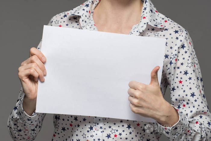 一个穿衬衣的女孩手里拿着一张白纸, 显示