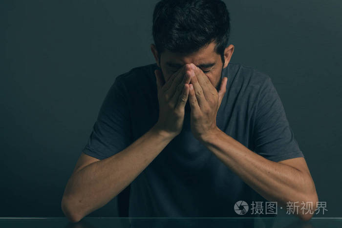 伤心的男人坐在黑暗的房间里.抑郁和焦虑障碍的概念