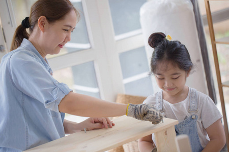亚洲可爱的女孩,帮助她的妈妈一起组装新 diy 家具放在家里照片