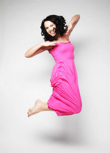 跳跃的女人。快乐情绪的女孩穿着粉红色的连衣裙