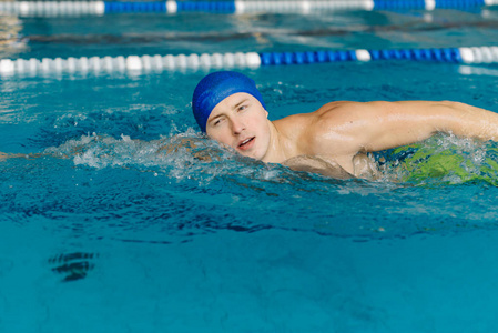 关闭了的年轻运动员在游泳池里游泳的照片
