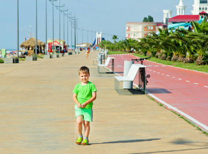 男婴在运动中，在阳光明媚的日子走在沙滩上