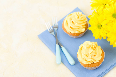 蓝餐巾黄色奶油蛋糕和小玻璃黄色菊花花束