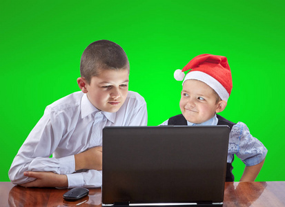 男孩子们正在坐在桌旁看一台笔记本电脑