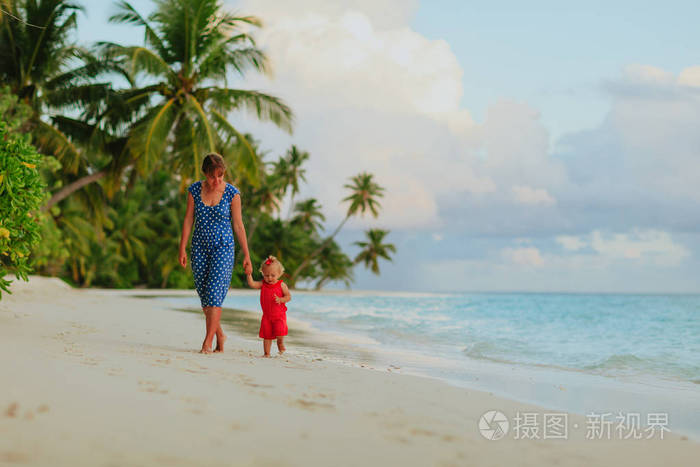 妈妈和可爱的小女儿在海滩上散步