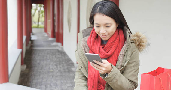 在中国园林中使用移动电话的女人