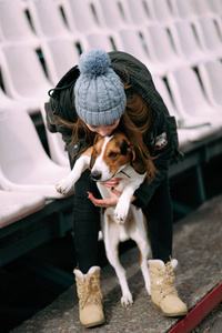 年轻的时髦女孩与她的宠物爱沙尼亚猎犬狗玩，俊平和拥抱和室外在玩老体育场