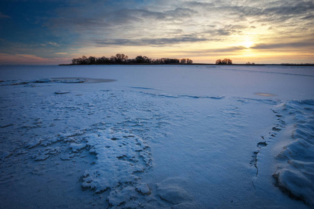 冬季景观与冰冻的湖面和落日的天空