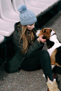 年轻的时髦女孩与她的宠物爱沙尼亚猎犬狗玩，俊平和拥抱和室外在玩老体育场