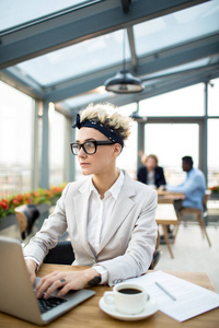 年轻的创意女性坐在桌前的笔记本电脑和寻找新的趋势在网上