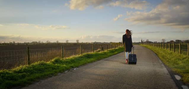 离家出走的少女,站在她的道路上的箱子照片