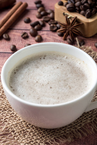 白咖啡杯和茶托牛奶泡沫和甘蔗糖肉桂茴香咖啡豆