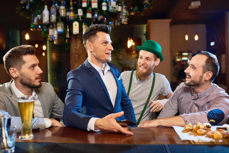 起劲一群开朗的朋友聊天起劲, 聚集在一起在酒吧和庆祝圣帕特里克节