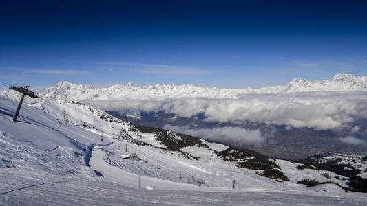 Chairlift 在意大利滑雪区的皮拉雪覆盖阿尔卑斯和松树在冬季与在法国的相思在背景可见