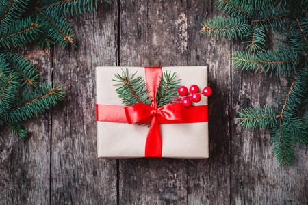 圣诞礼品盒红丝带，冷杉的枝条，雪花飘落在木制的背景。圣诞节和新年快乐组成。平躺，顶视图
