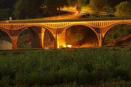 夜的场面桥梁和人野营地方与火在夏天。罗马尼亚