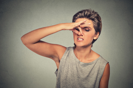 女人用手指捏着鼻子,厌恶地看着照片