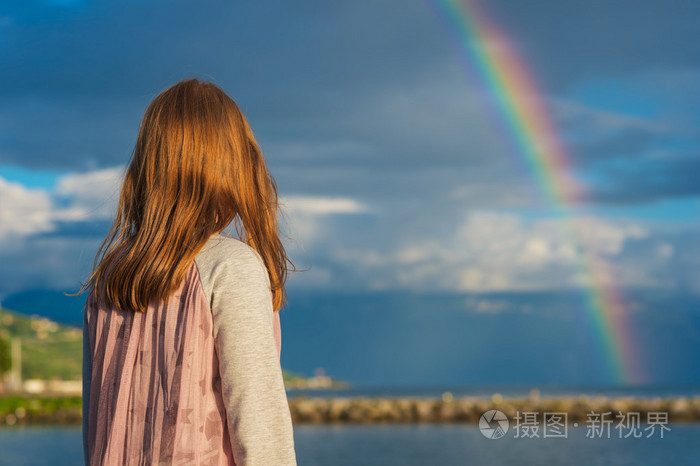 一个可爱的小女孩,看彩虹的室外肖像