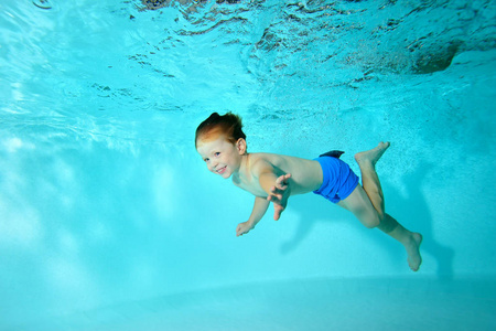 快乐的婴孩游泳在水下在水池和笑。肖像。水平视图