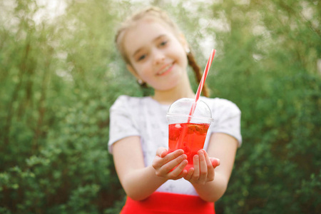 美丽的女孩微笑着, 手里拿着一杯草莓饮料。