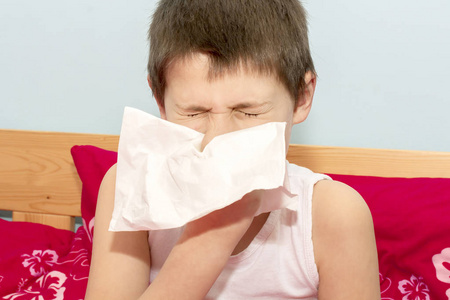 那个生病的男孩把他的鼻子吹进手帕里。