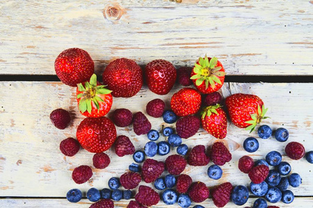 健康的混合水果和配料与草莓, 覆盆子, 蓝莓从顶部的看法。在质朴的白色木质背景浆果。平面设计。文本的可用空间。为横幅复制空间