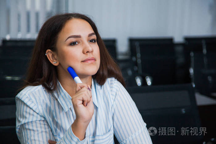 女学生在空教室里坐着仔细听.年轻的卷发妇女在办公室桌在礼堂